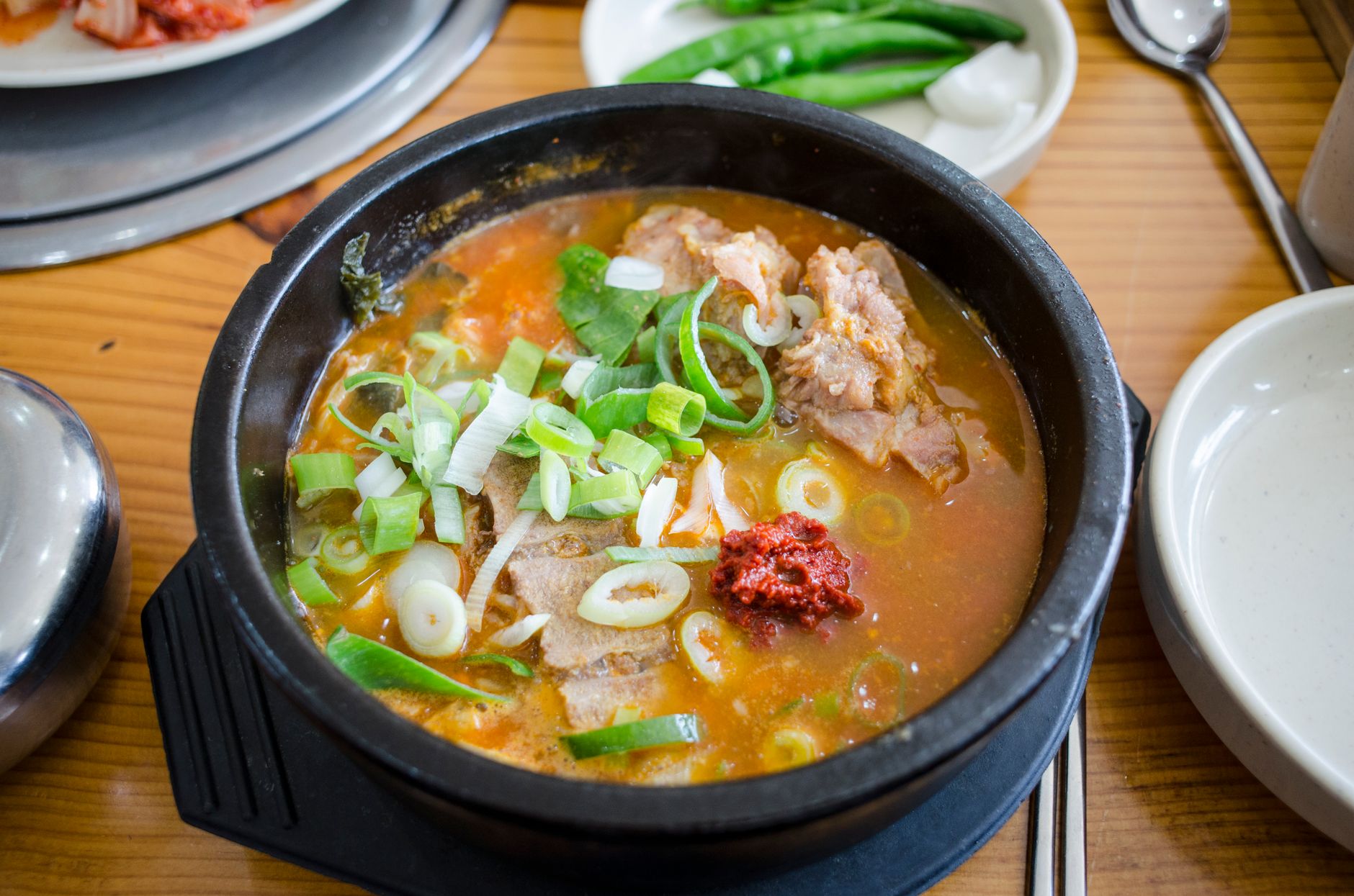 Close-up of flavorful Korean haejangguk soup garnished with fresh scallions, served hot in a traditional bowl.