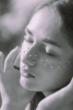 Artistic black and white portrait of a young woman with natural beauty and delicate petal accents.