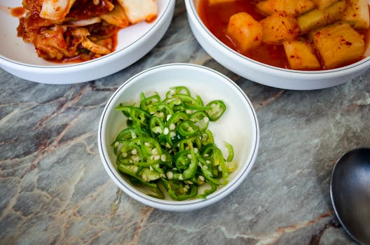 A close-up of Korean side dishes in white bowls, showcasing fresh ingredients and vibrant flavors.