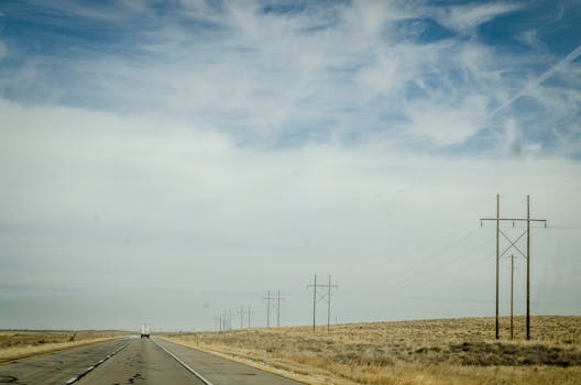 广阔的蓝天下，电线沿着孤独的沙漠高速公路延伸