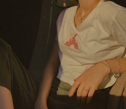 Stylish young woman wearing a print t-shirt, ring, and bracelets in sunlight.