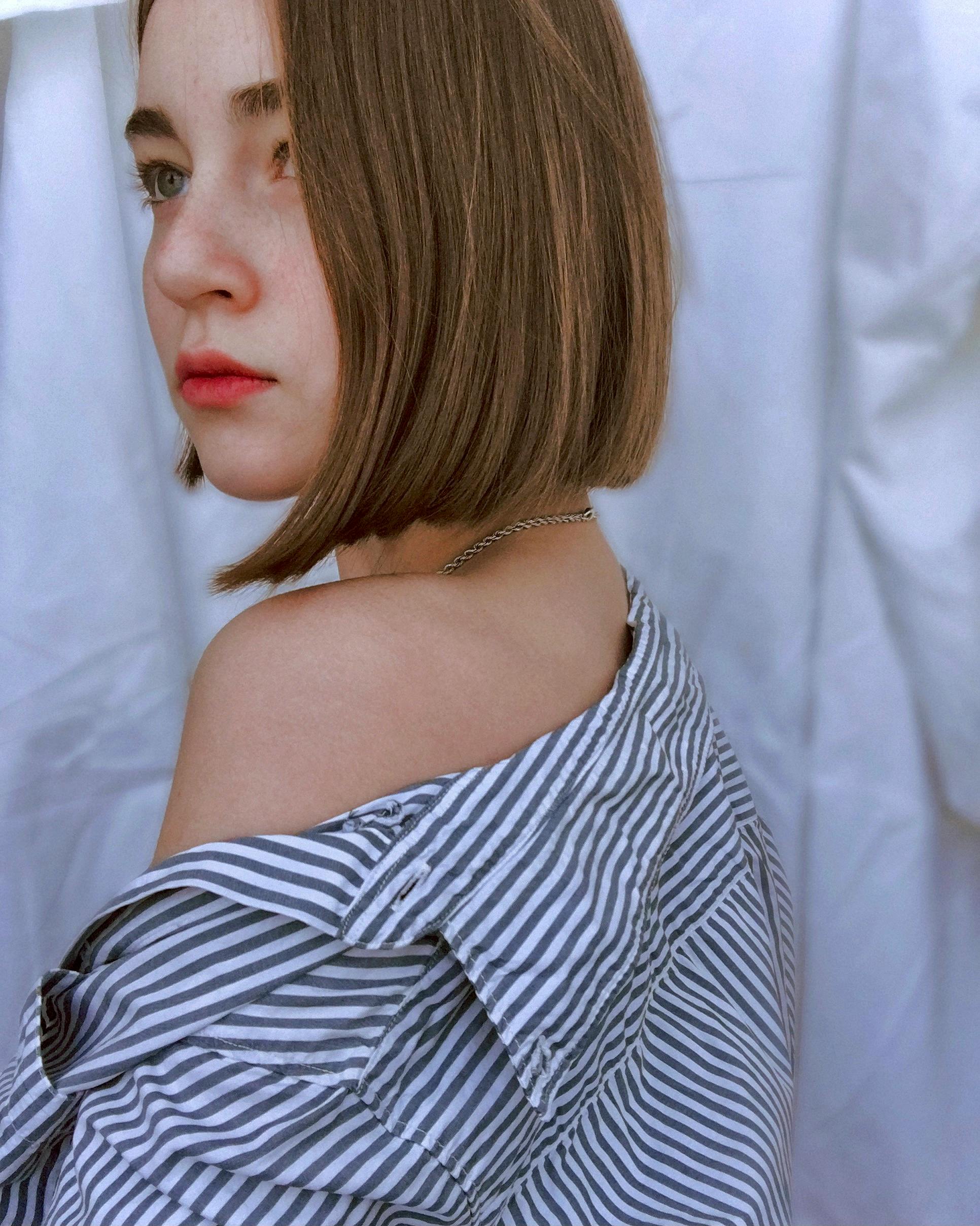 a woman in gray and white stripe shirt showing her shoulder