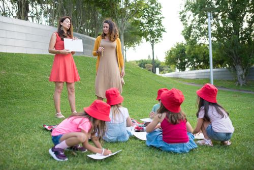 Free Girls engaged in an outdoor educational activity with two women educators. Stock Photo