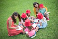 Two Women Sitting On Grass With Children  Spending Leisure Time