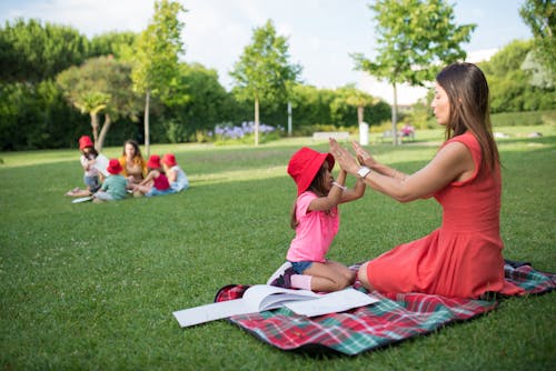 Woman in Red Dress Playing with a Girl Wearing Pink Shirt and Red Bucket Hat
