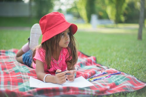 Close-Up Shot of Girl Lying Down on a Picnic Blanket on Grass