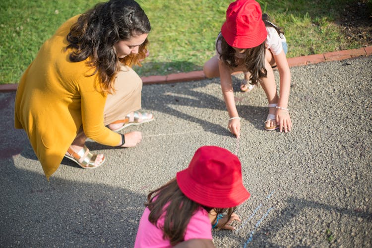 A Woman With Children Drawing On The Floor