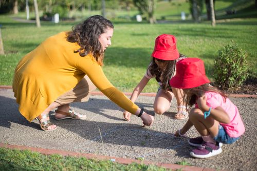 Free A nanny and two children drawing with chalk on a sunny day outdoors. Stock Photo