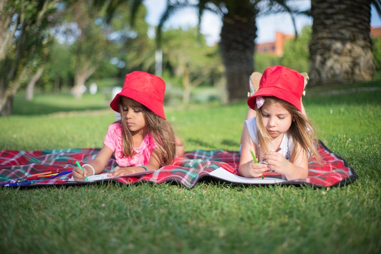 Two Girls Wearing Red Hat While Writing 