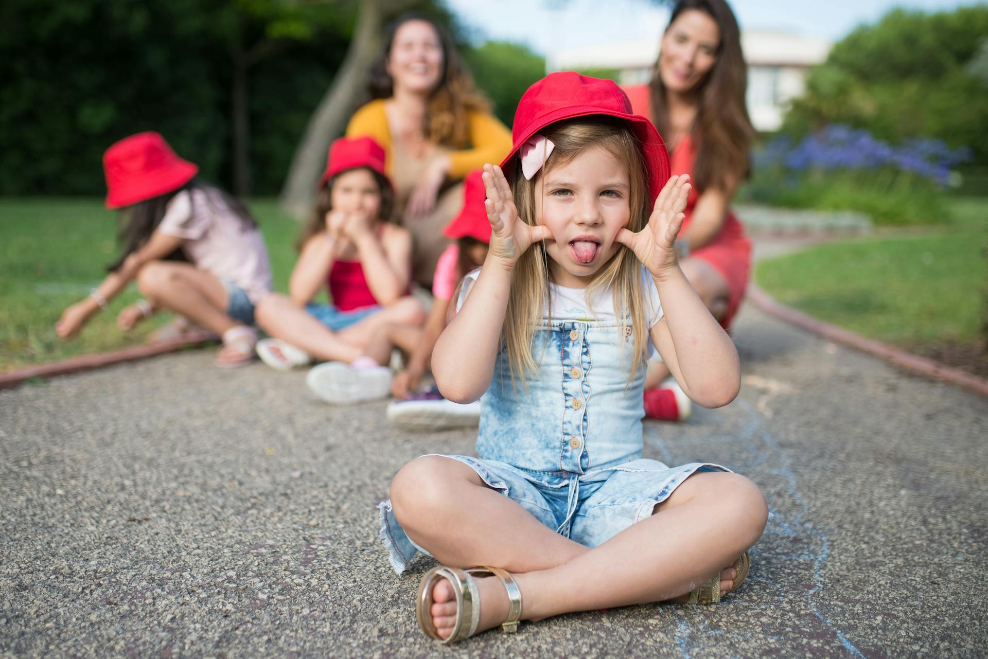 Close-Up Shot of a Girl with Red Hat Sitting on the Ground