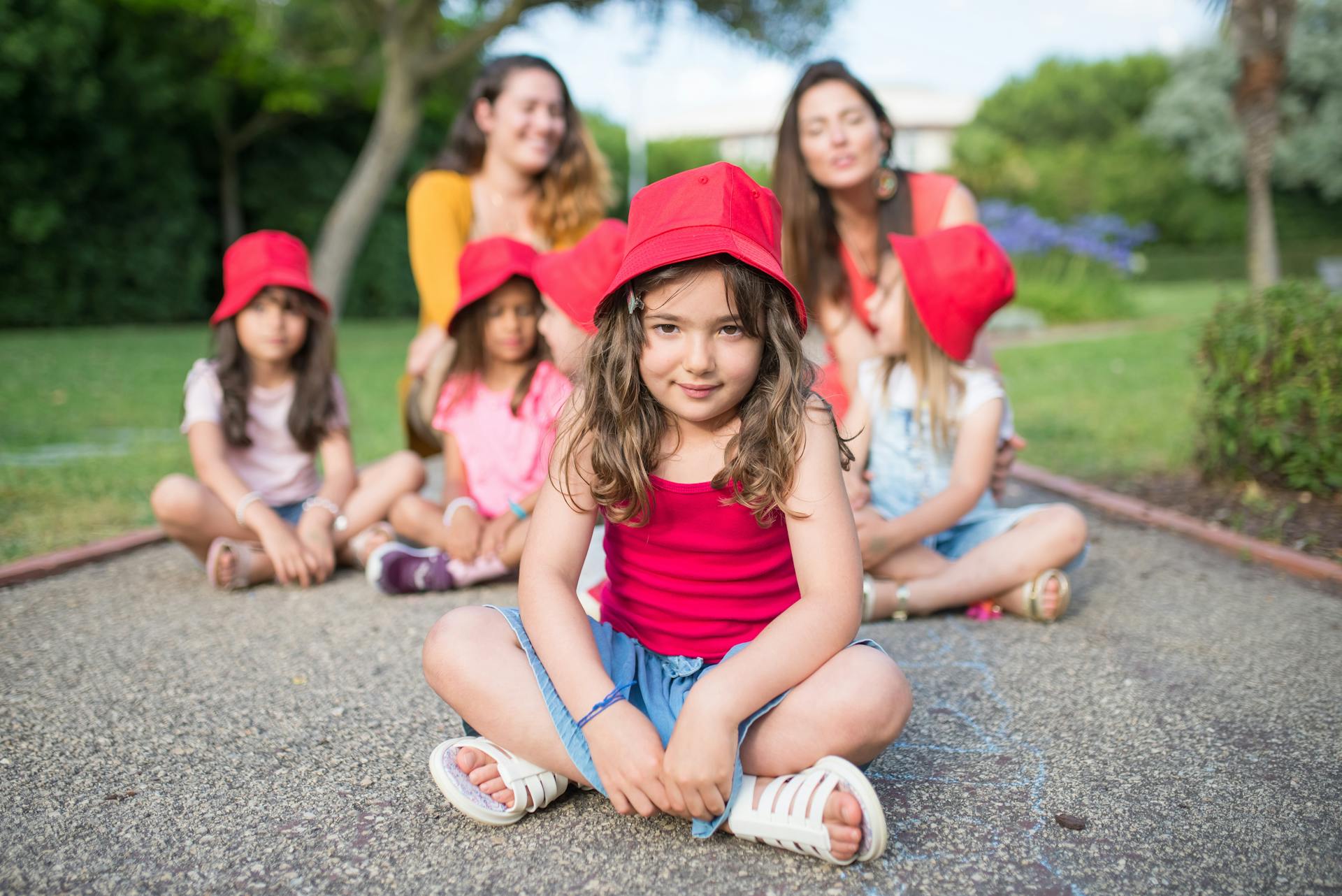 A Young Girl Wearing a Red Hat Sitting on the Floor