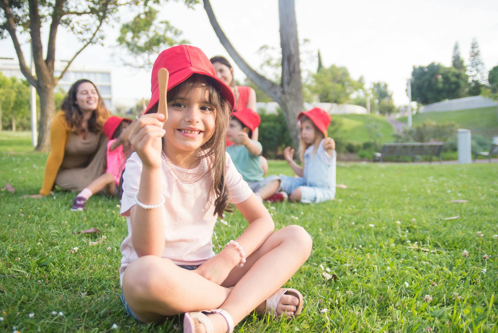 Young children enjoying a sunny day with red hats in a vibrant park setting.