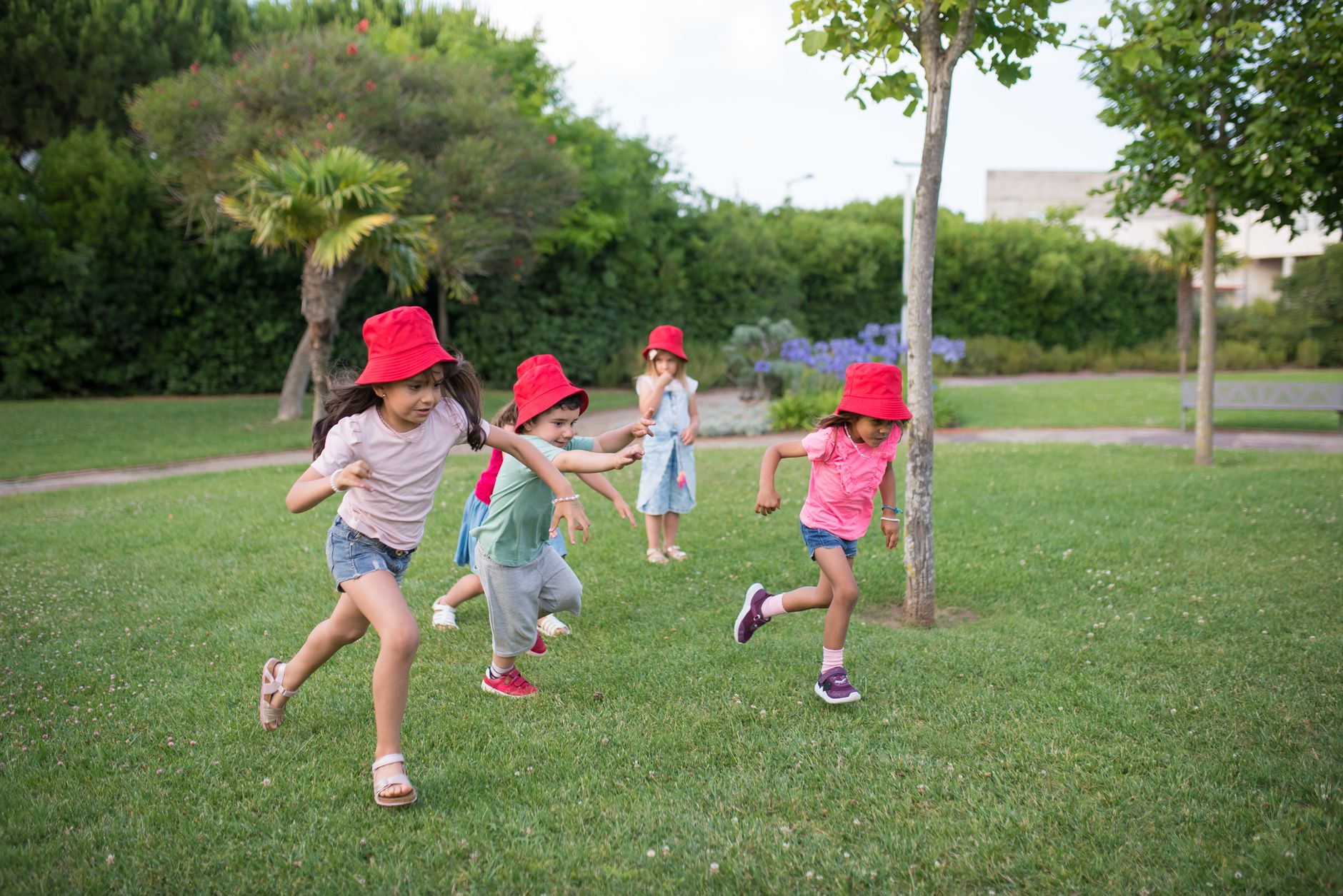 American school family day New Cairo — Group of children having fun in a sunny park in Portugal, wearing red hats