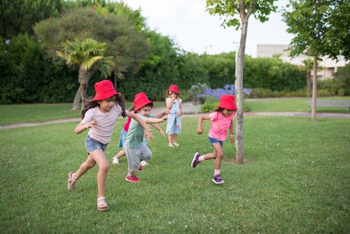 Free Group of children having fun in a sunny park in Portugal, wearing red hats Stock Photo