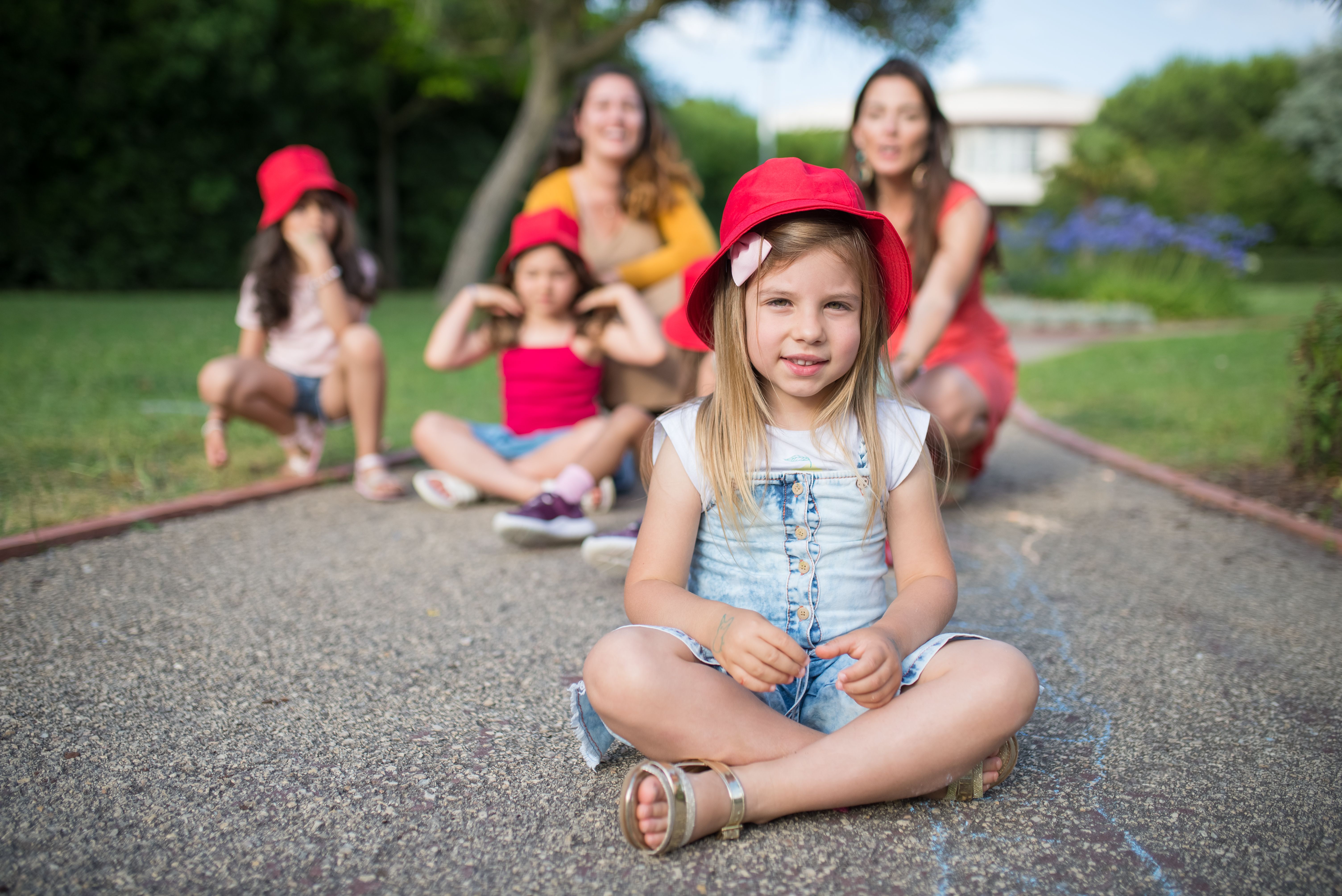 American school family day New Cairo — A group of smiling children wearing red hats enjoy a playful day outdoors in Portugal.