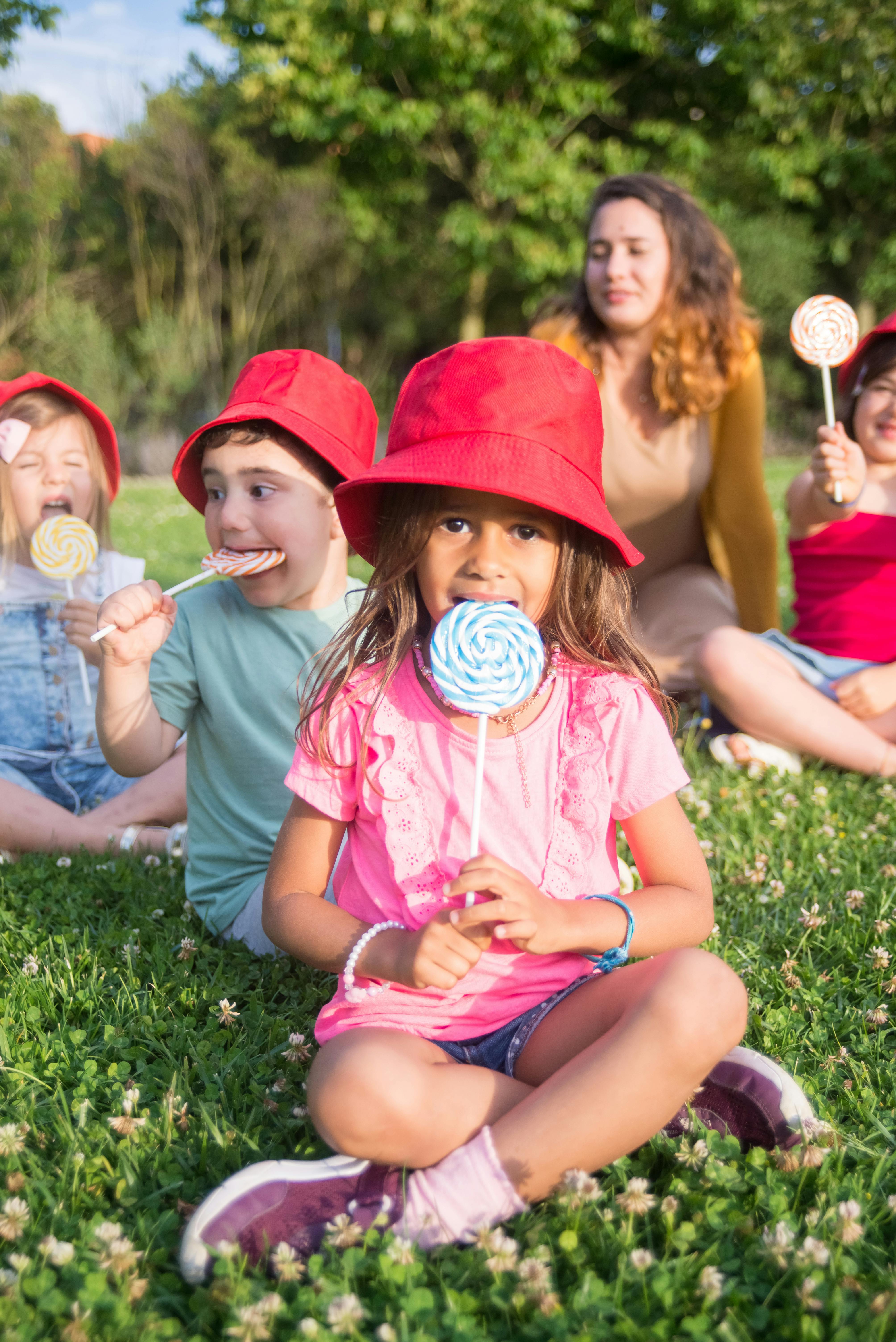 CloseUp Shot of a Girl Eating Candy while Sitting on Grass · Free