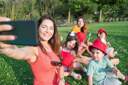 Woman Taking a Group Selfie while Sitting on Grass