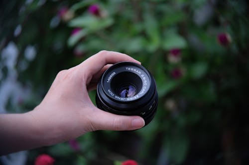 Close-Up Shot of a Person Holding Camera Lens