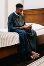 Man Wearing Soutane Sitting on the Bed