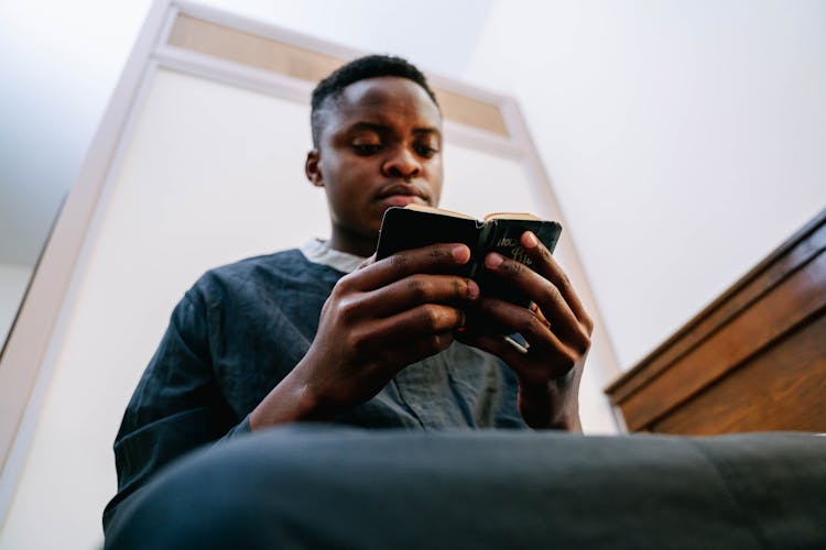 Man Wearing Black Soutane Reading A Bible