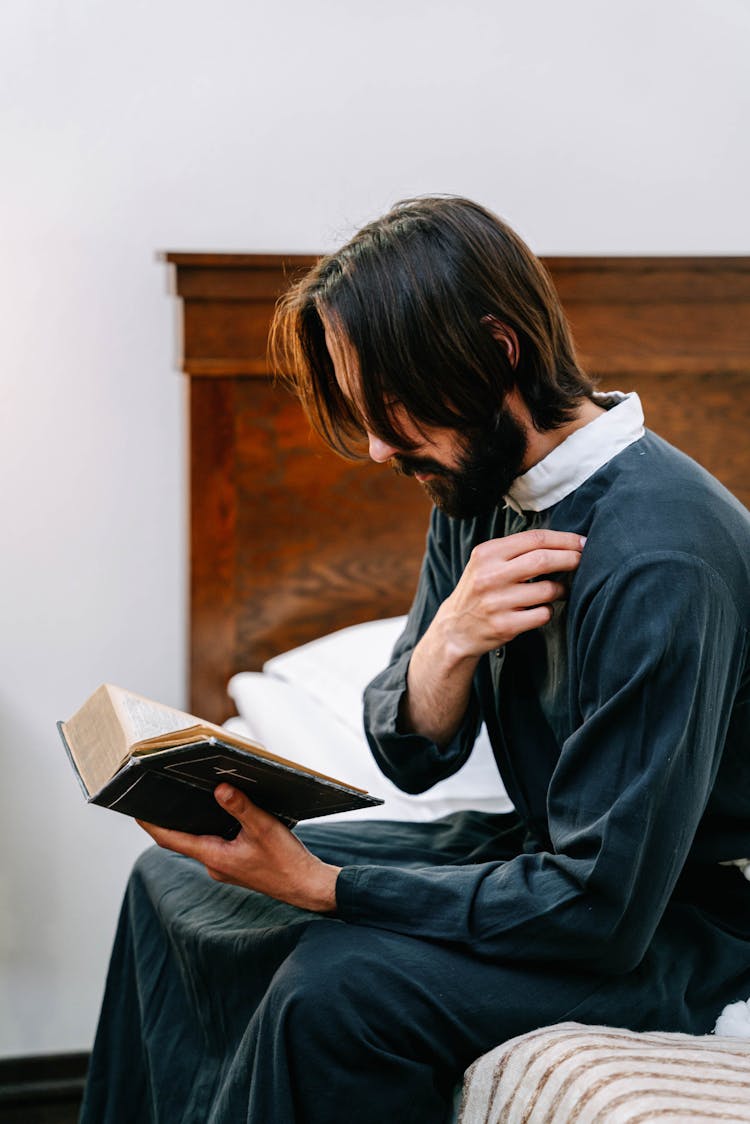 A Bearded Man In Blue Robe Holding A Bible Making Sign Of The Cross 