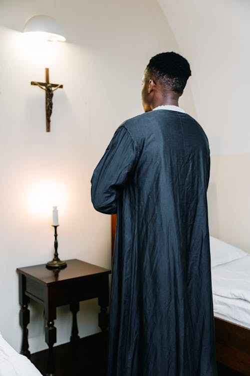 Free Man in Black Robe Standing in Front of the Cross Stock Photo