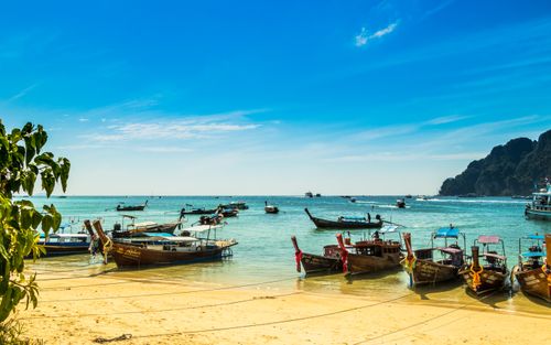 Free Vibrant long-tail boats docked on a sunny beach in Thailand, under a clear blue sky. Stock Photo