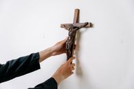 A Person Holding a Wooden Cross on a Wall