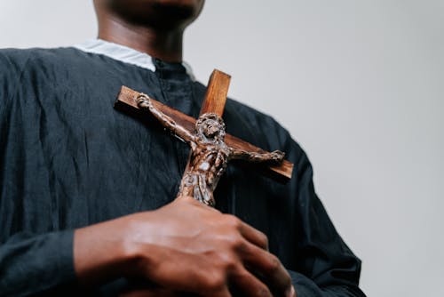 Man Wearing Cassock Holding a Cross