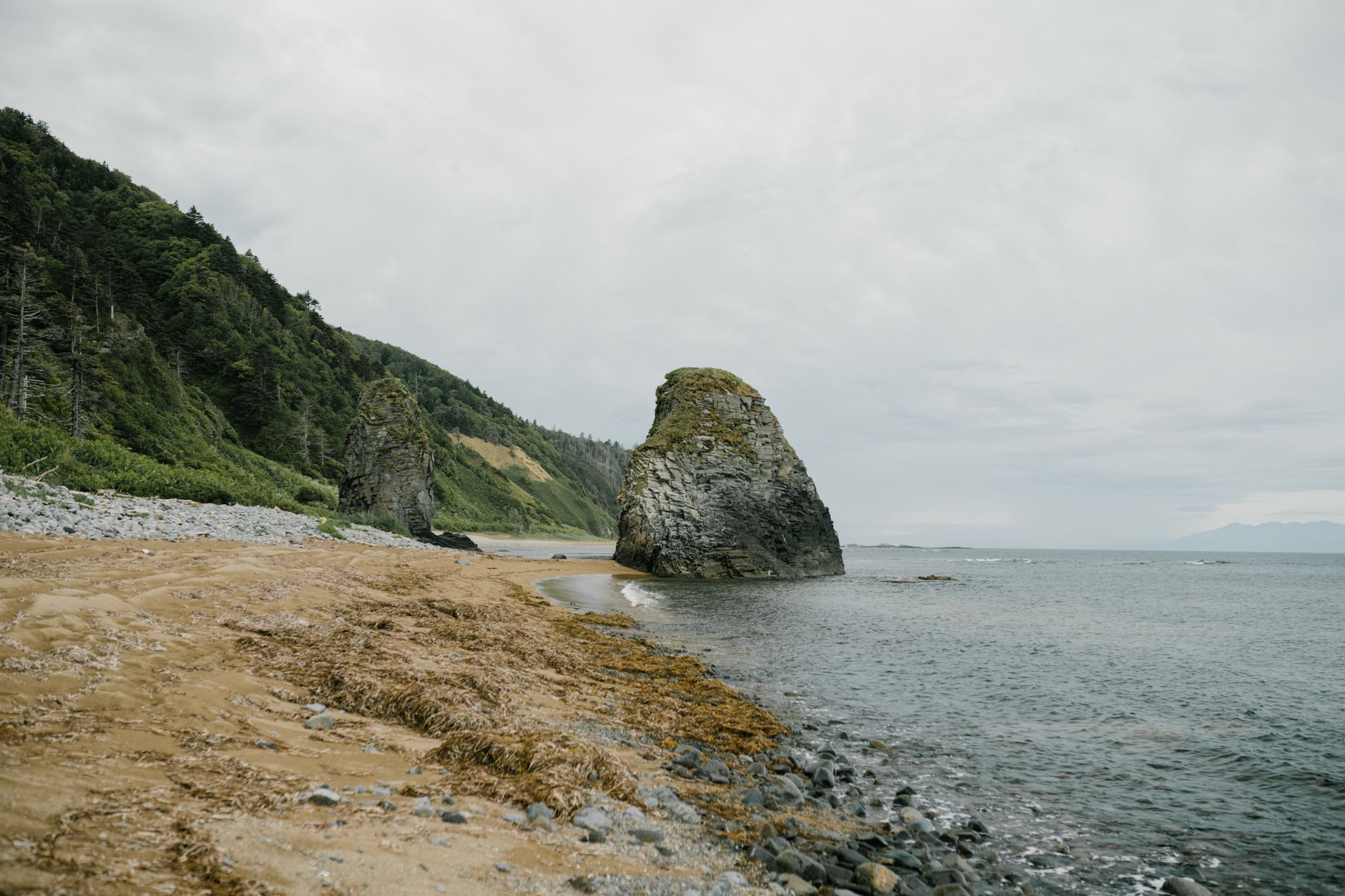 Explore the natural beauty of Sakhalin's coastline with rocks and sea under overcast skies.