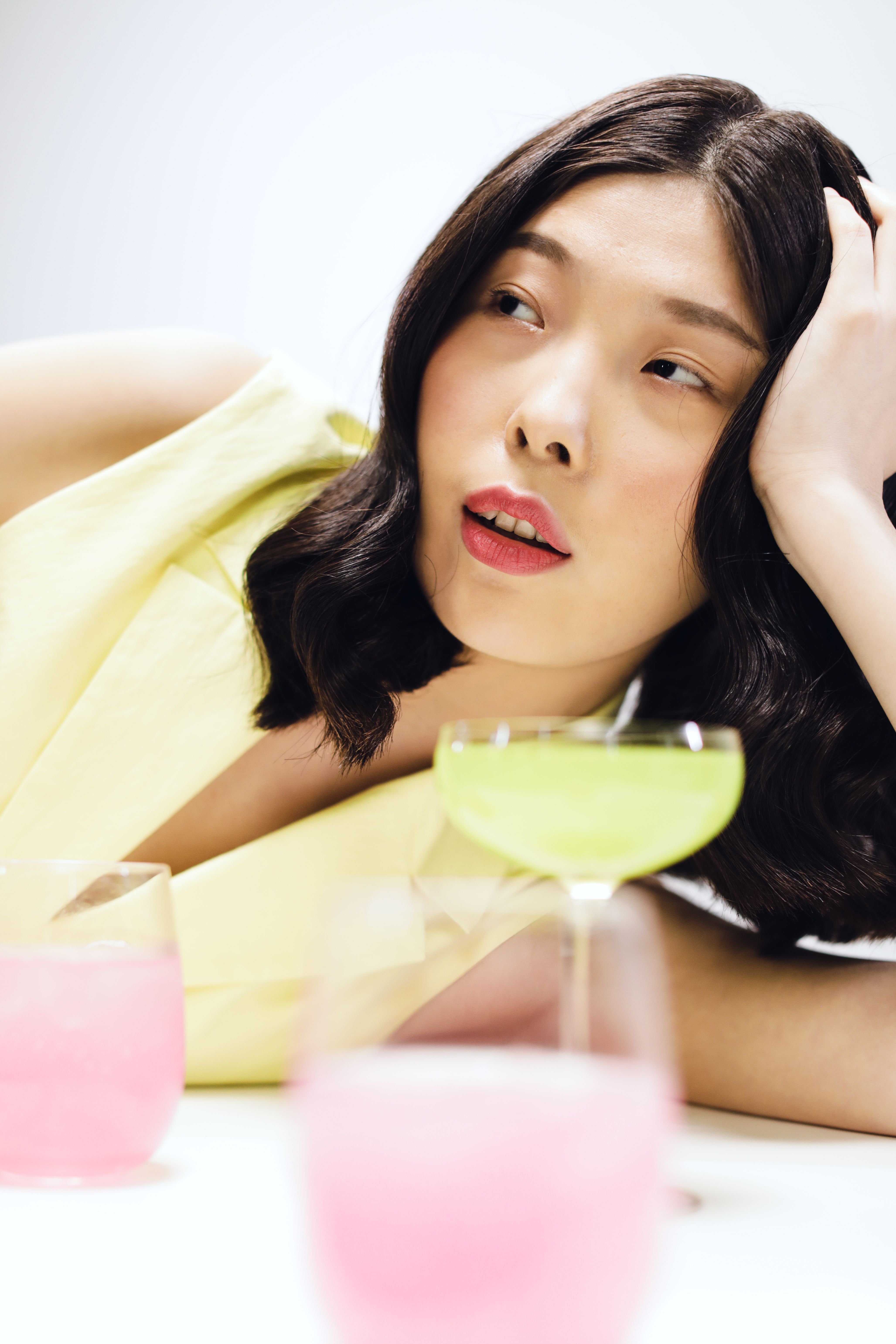 Elegant woman relaxing with colorful cocktails on a white background.