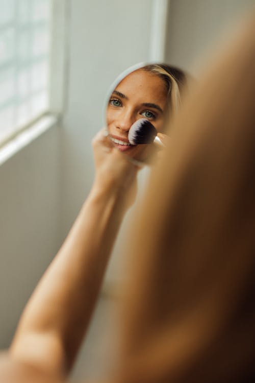 Woman Putting Make Up in Front of a Mirror