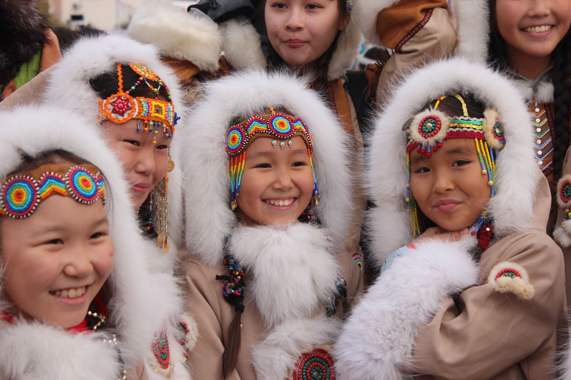 Smiling girls in vibrant traditional attire celebrating together outdoors.