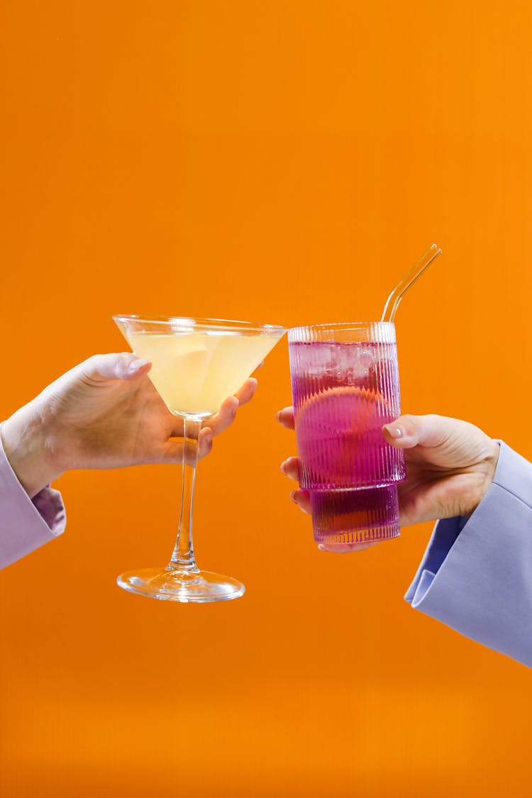 People Holding Cocktails In A Glass