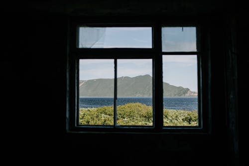 A Glass Window with a Mountain View Near the Body of Water