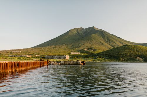 Free Scenic view of lush green mountains by a calm lake on Sakhalin Island, Russia. Stock Photo
