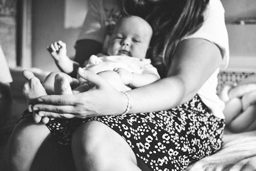 Grayscale Photo of a Person Holding a Baby