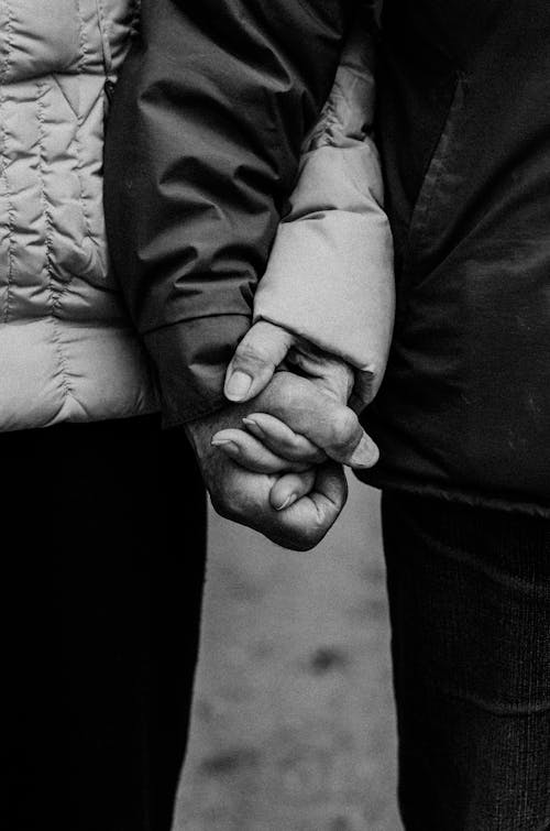 Grayscale Photo of Man and Woman Holding Hands