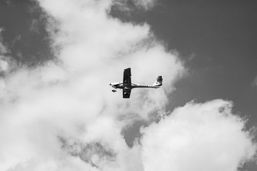 Free Black and white photograph of a Cessna flying amidst clouds, showcasing its mid-air elegance. Stock Photo