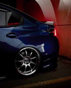 Stylish sports car with prominent rims and tail light in a moody urban location, ideal for auto enthusiasts.