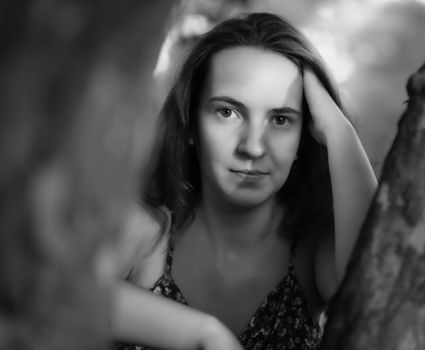 A captivating black and white portrait of a woman posing thoughtfully outdoors.