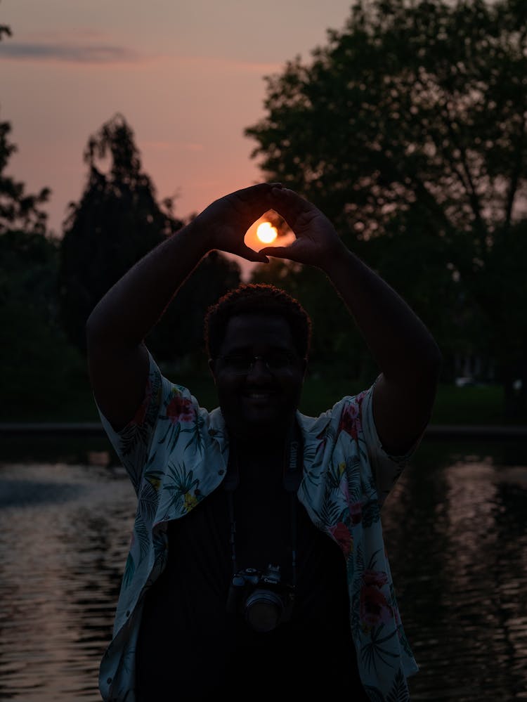 A Man Framing The Sun With His Hands