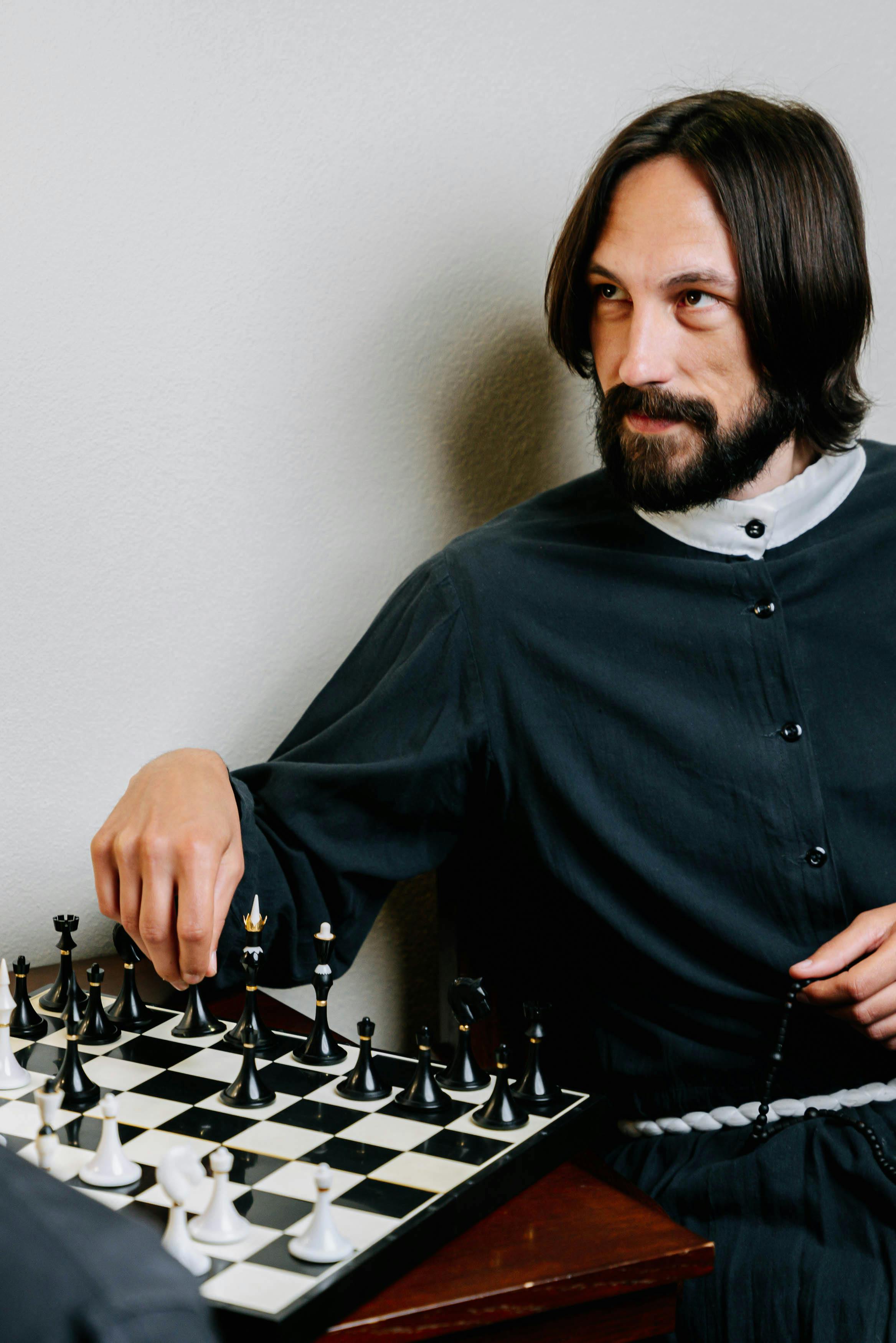 a bearded man in black and white shirt playing chess