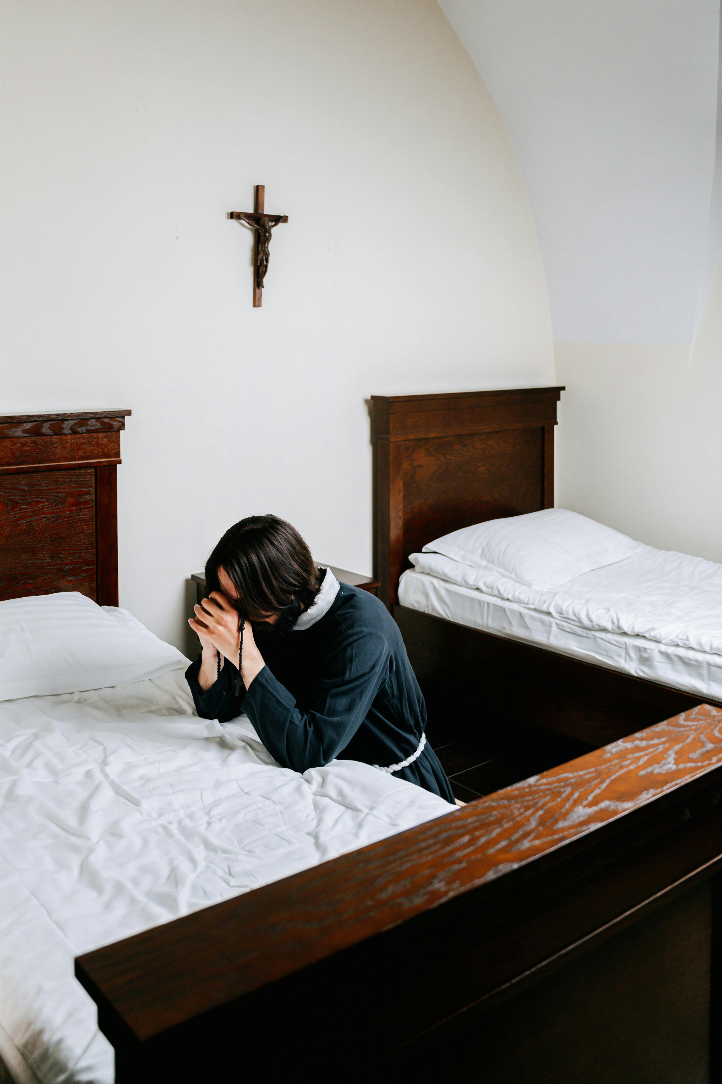 man praying beside a bed