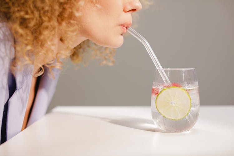 Woman Sipping From Clear Glass With Antioxidant Drink