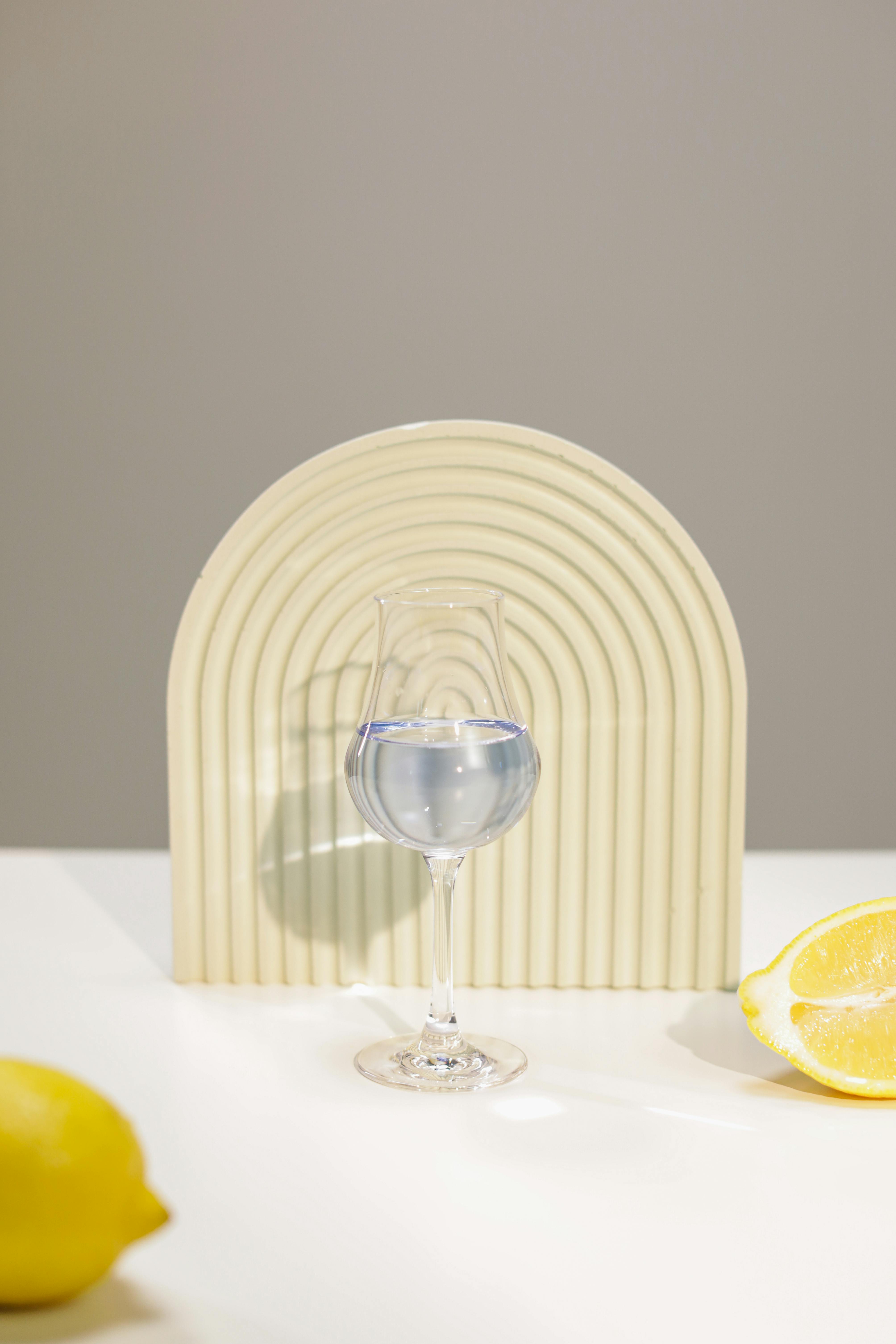 A modern still life with lemon slices and a wine glass on a white table.