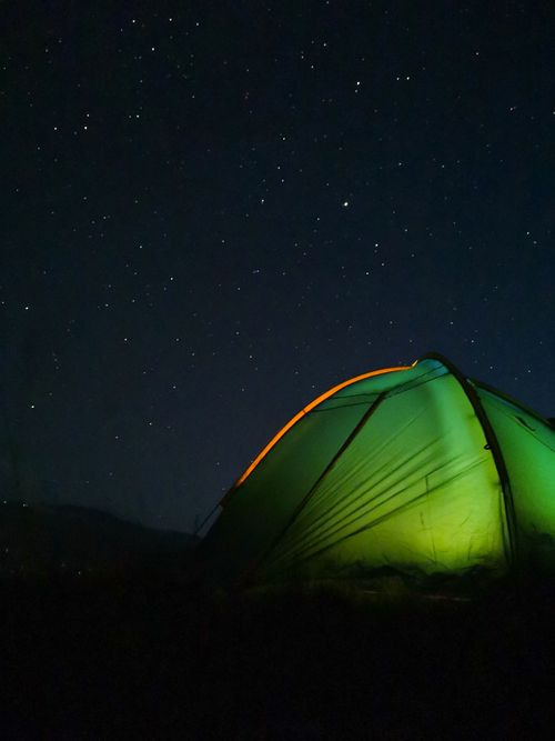 Free A green tent illuminated under a vast starlit sky in the Russian wilderness, perfect for night adventures. Stock Photo