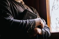 Person in Black Leather Jacket Holding Black Book