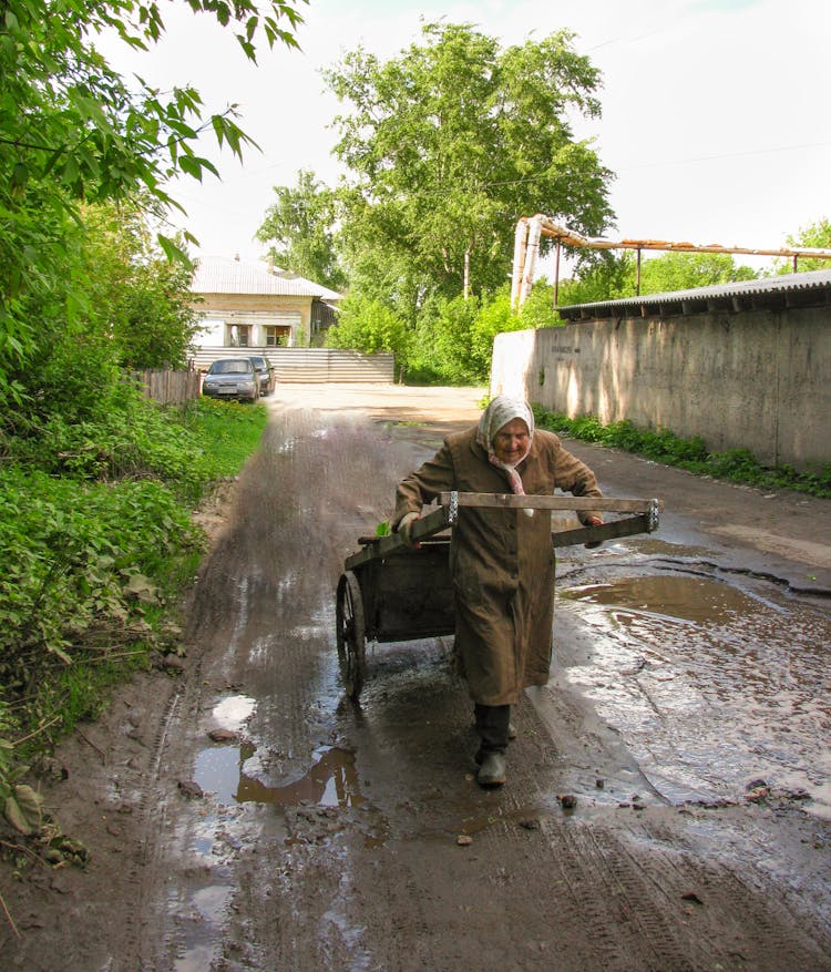 Woman Pulling A Cart On A Muddy Street