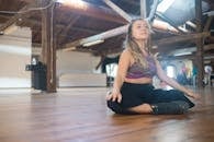 Woman in Gray Tank Top and Black Denim Jeans Sitting on Brown Wooden Floor